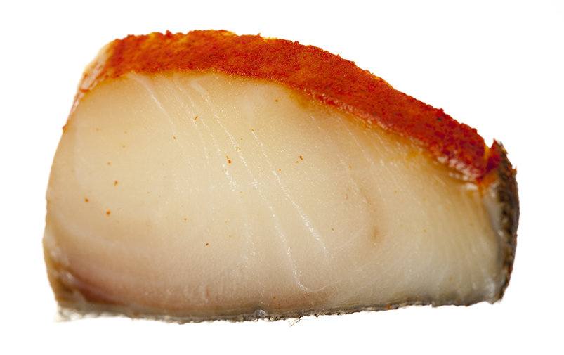 A beautiful slab of smoked sable lays glistening on matte white surface.