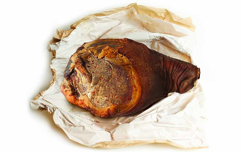 A hunk of American country ham bursts forth from some butcher paper