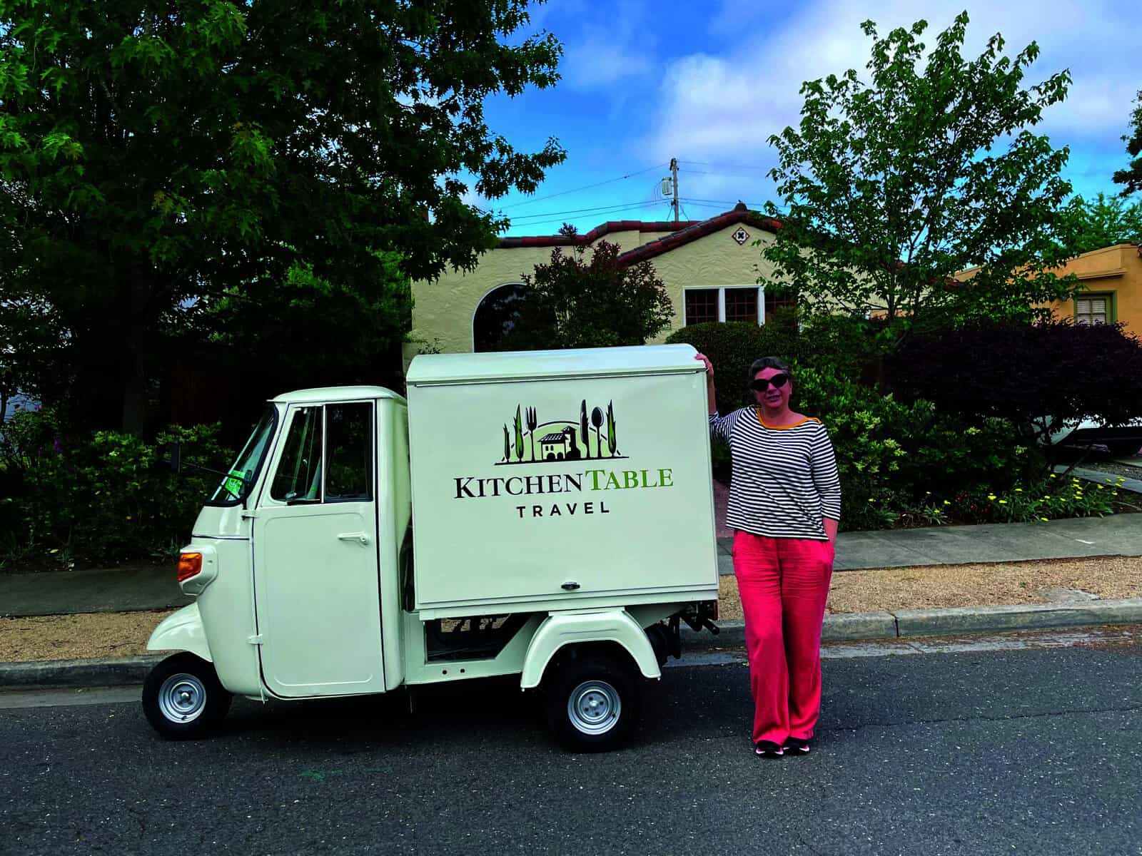 A woman stands in front of a white truck.